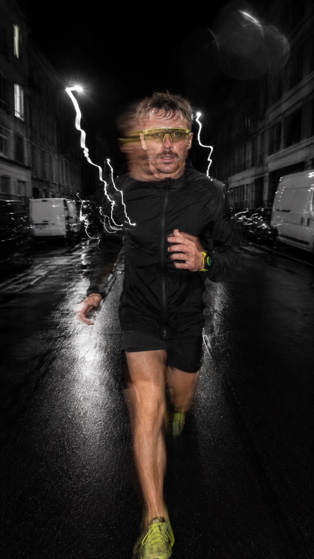 Une rue étroite de nuit, les pavés luisants de pluie, un coureur seul dans des éclats de lumière blanche.